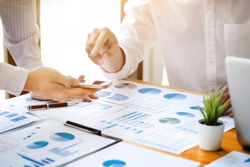Two analysts reviewing charts and reports on a desk during a corporate risk audit in the UAE