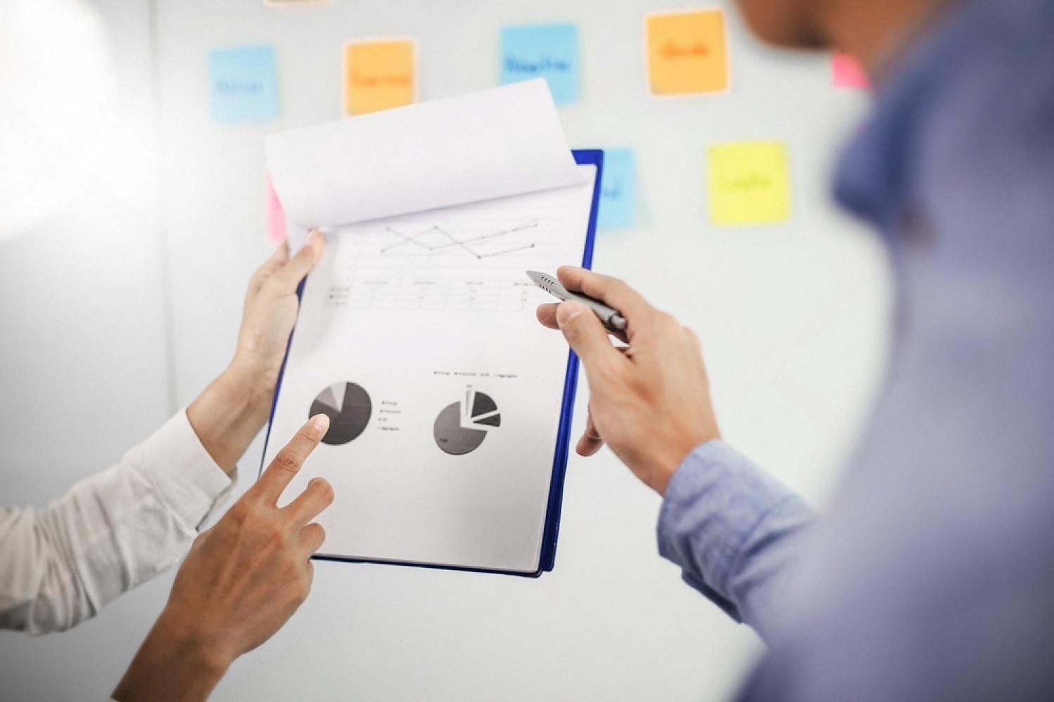 Consultants examining pie charts and graphs in a printed risk audit report